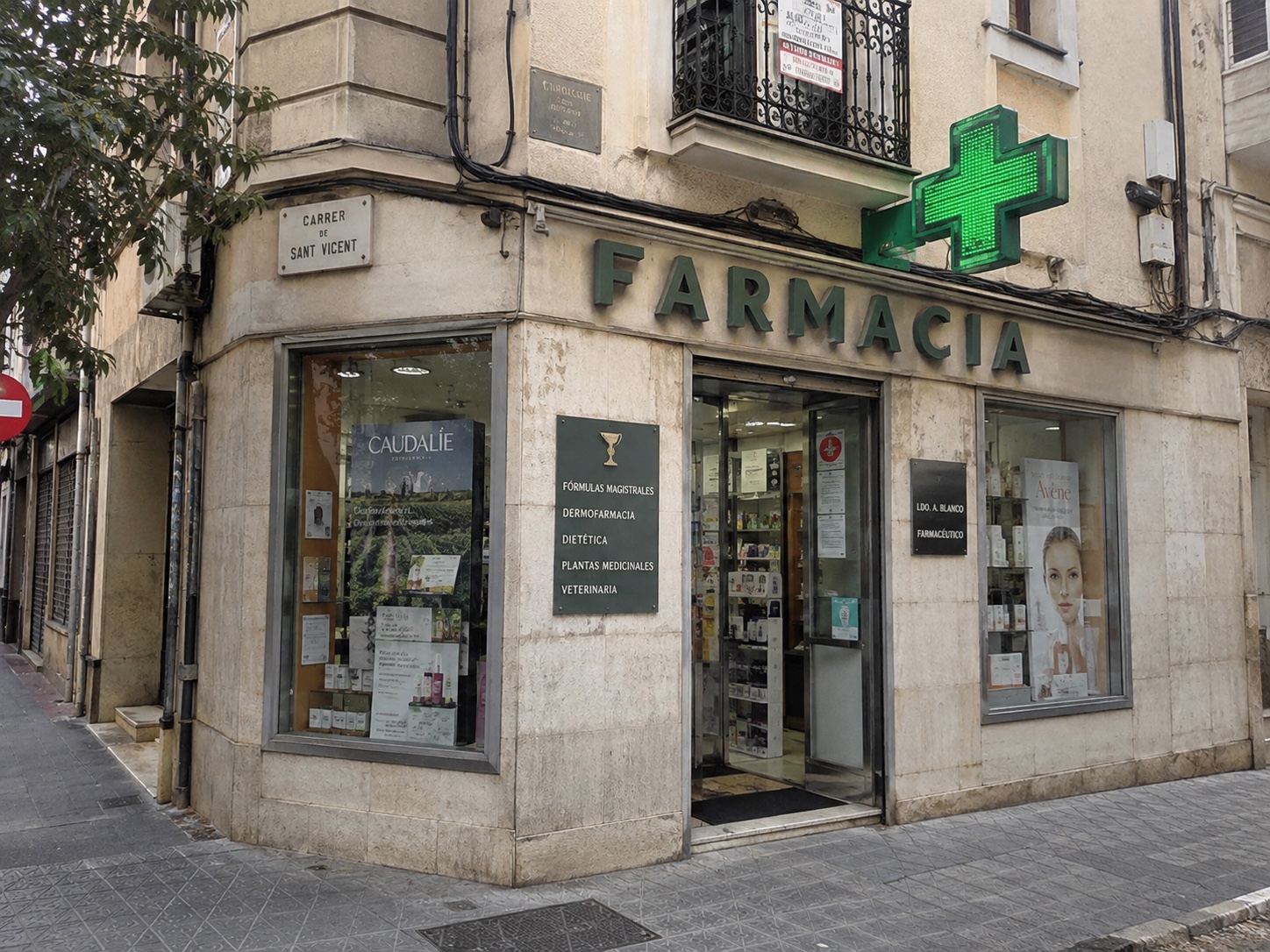 Fachada antes de la reforma, con revestimiento de piedra y rótulo verde.